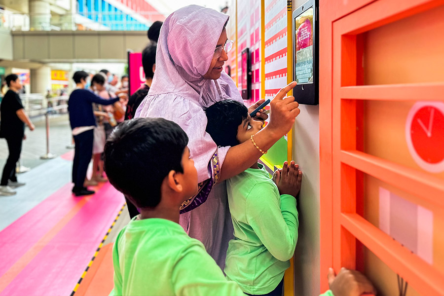 A mother and her children at the UNiTEA Vending Machine, where Singaporeans can enjoy dispensed drinks when they share their unique Singaporean experiences 